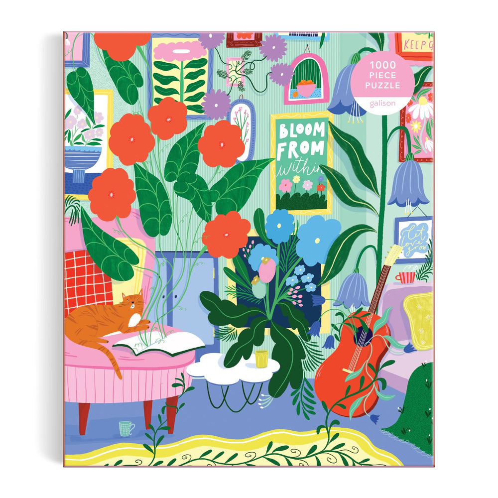 The Jessica Smith "Room to Bloom 1000 Piece Puzzle" features a vibrant illustration of a cozy living room with lush plants, blooming flowers, a red cat on a pink chair, guitar, and wall art saying "BLOOM FROM WITHIN.