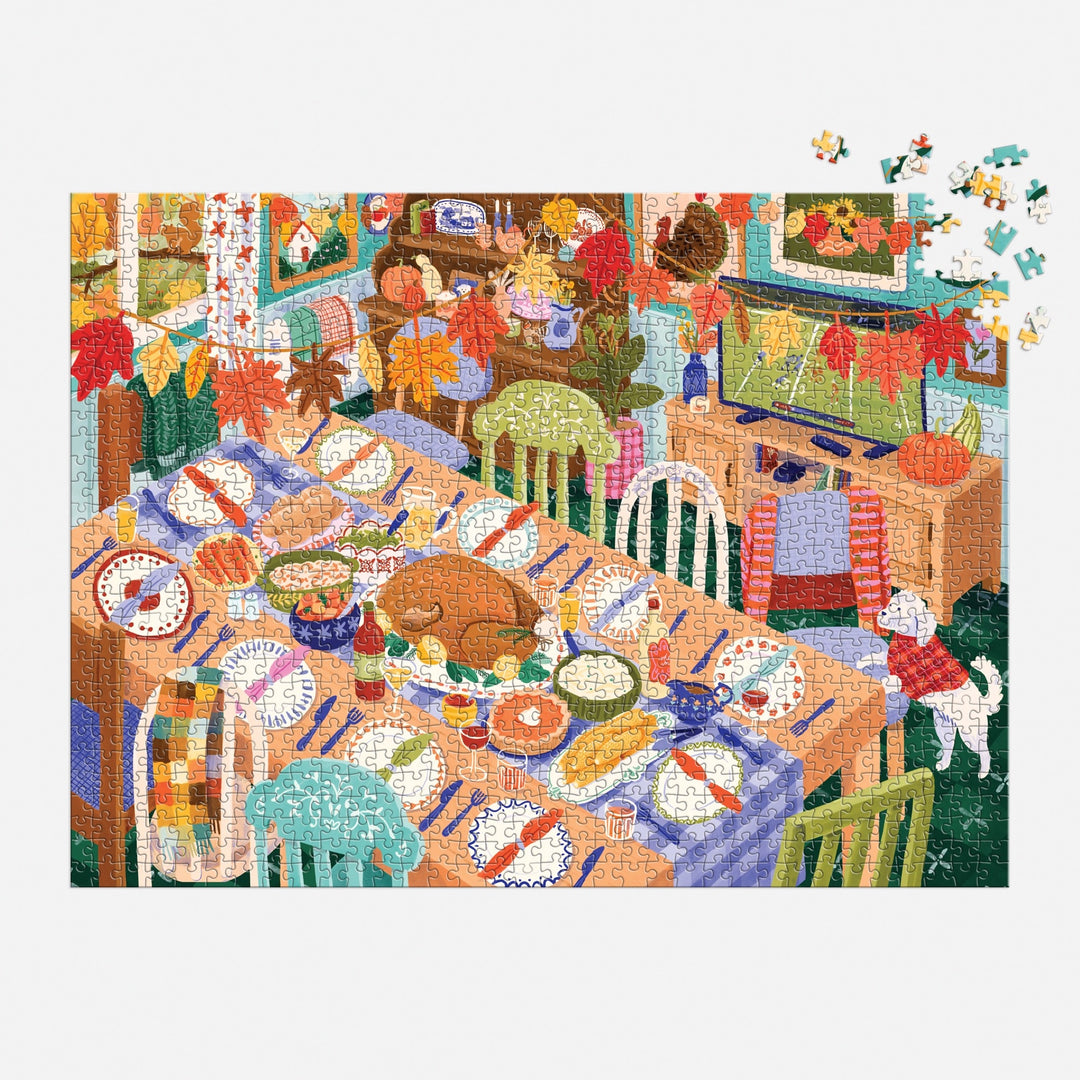 The Carla Ellis Thankful Table 1000 Piece Puzzle features a festive dining table with assorted dishes, mismatched chairs, fall decor, a dog by the window, and missing pieces in the top right for an engaging challenge.
