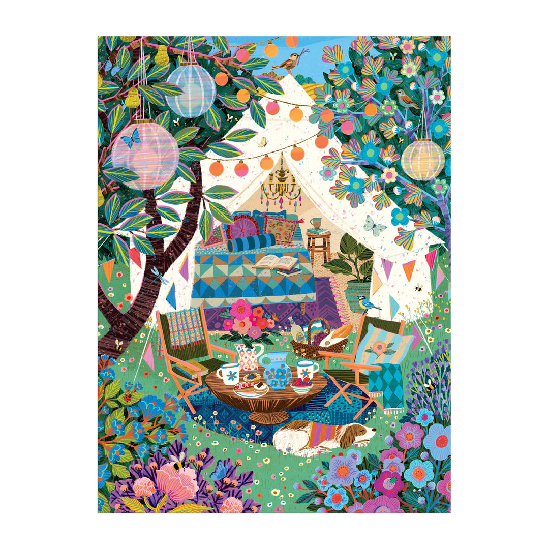 The Victoria Ball Blooming Escape 1000 Piece Puzzle features a cozy outdoor tent with lanterns, bunting, lush flowers, and trees. Inside are chairs, a tea set table, a comfy bed with pillows, and a white dog resting on the grass.
