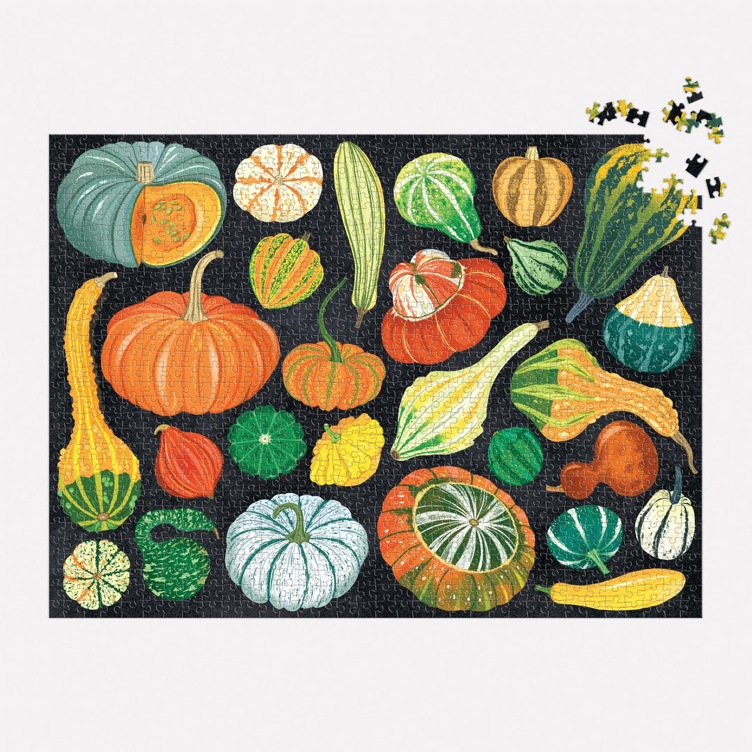 The World of Pumpkins 1000 Piece Puzzle by Dawn Cooper features vibrant illustrations of pumpkins and gourds on a black background, with several loose pieces visible in the top right corner.