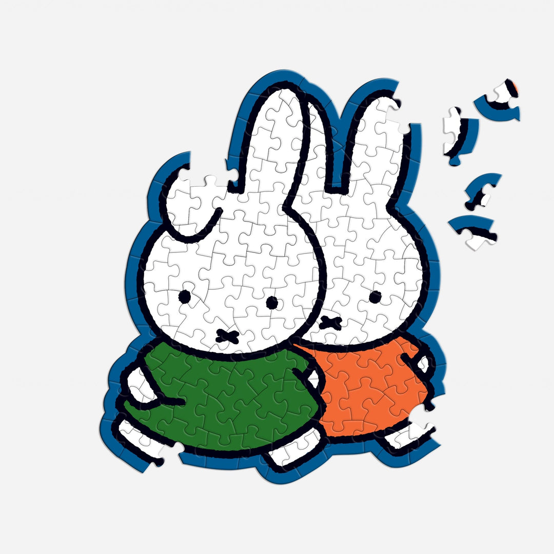 The Miffy 100 Piece Surprise Puzzle by Miffy shows two white cartoon bunnies—one in green, one in orange—standing side by side. The puzzle is partially completed with a few pieces missing on the right side.