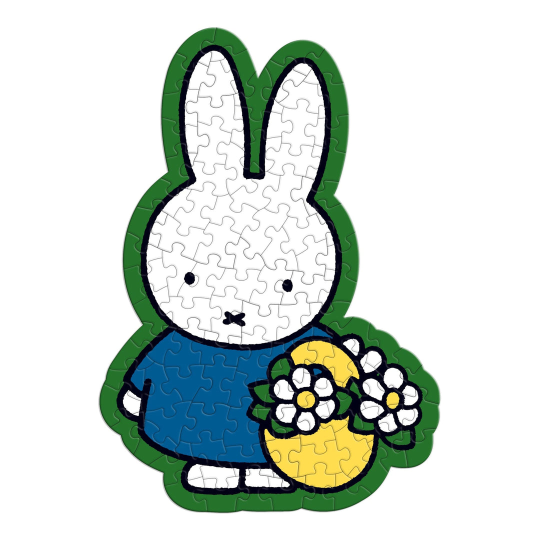 The Miffy 100 Piece Surprise Puzzle by Miffy features a white cartoon bunny in a blue dress holding a yellow basket with white flowers. The puzzle has clearly outlined pieces and a clean white background.