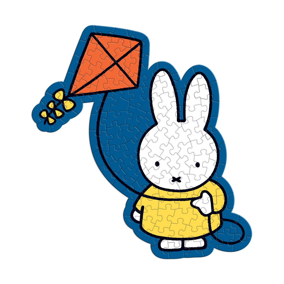 The Miffy 100 Piece Surprise Puzzle by Miffy features an illustration of a white rabbit in a yellow dress holding a red kite with a yellow tail, depicted as a jigsaw puzzle with visible piece outlines.