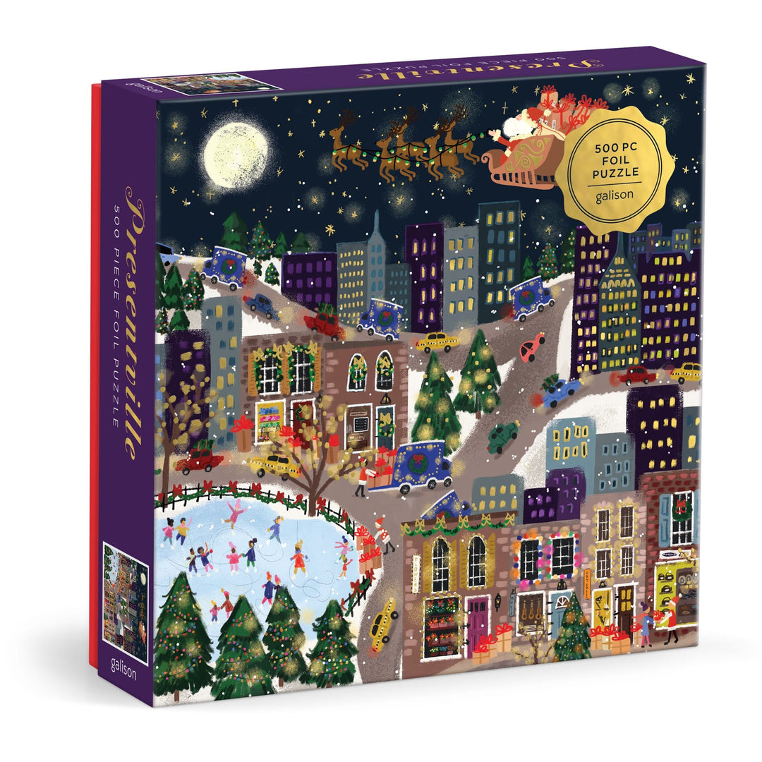The Joy Laforme Presentville 500 Piece Foil Puzzle features a festive cityscape with people ice skating, decorated buildings, Christmas trees, and Santa’s sleigh flying over snowy rooftops beneath a full moon.