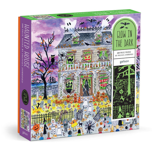 The Michael Storrings Haunted House 500 Piece Glow in the Dark Puzzle features ghosts, pumpkins, skeletons, and bats—perfect for intermediate puzzlers and branded by Michael Storrings.