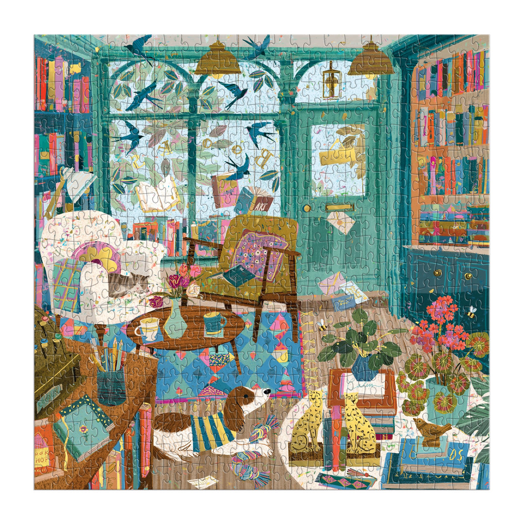 Enjoy Victoria Ball’s Bookshop Afternoon 500 Piece Foil Puzzle, featuring a vibrant living room brimming with books, plants, armchairs, a dog lounging on the floor, and birds outside—ideal for literary lovers and puzzle fans alike.