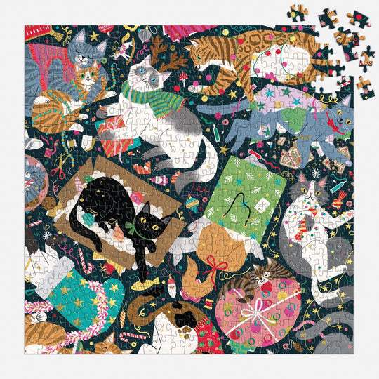The Catmas Chaos 500 Piece Foil Puzzle by Maria Kee showcases playful cats in festive scenes with ornaments, yarn, gifts, and decorations. Just a few pieces remain to finish the holiday cat puzzle’s top right corner.