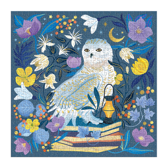 The Dawn Cooper Celestial Owl 500 Piece Foil Puzzle features a white owl surrounded by vibrant flowers, books, a lantern, and stars on a deep blue background with yellow, purple, and orange floral details.