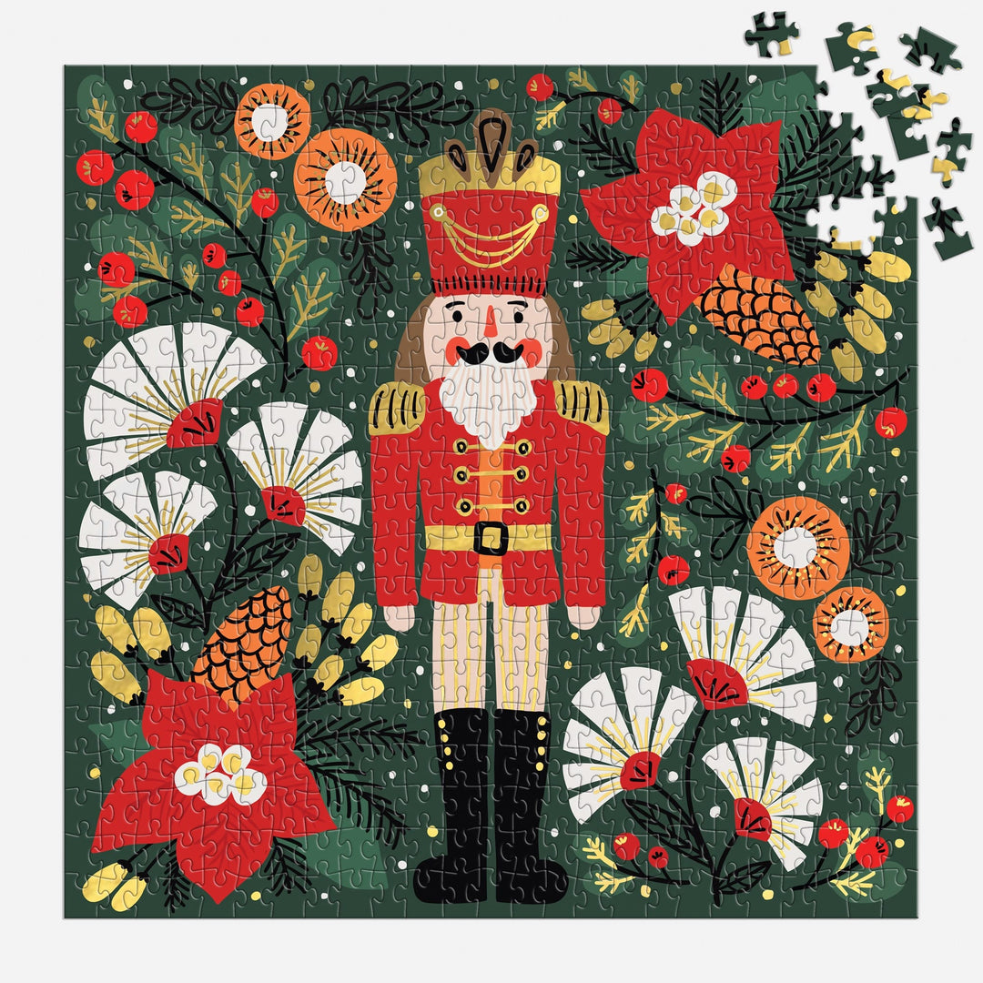 The Sandra Hutter Merry Nutcracker 500 Piece Foil Puzzle features a festive red-uniformed nutcracker amid holiday florals—perfect for collectors and seasonal art lovers looking for a vibrant, high-quality holiday puzzle.