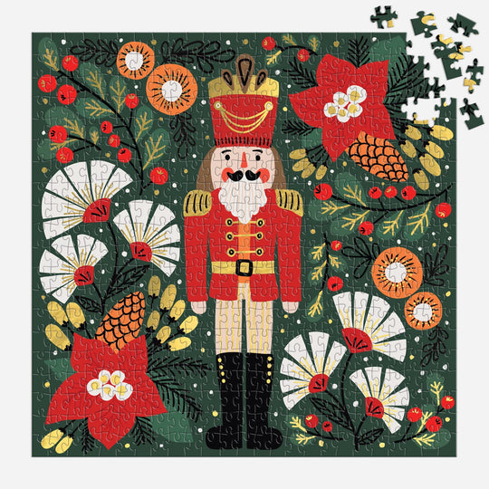 The Sandra Hutter Merry Nutcracker 500 Piece Foil Puzzle features a festive red-uniformed nutcracker amid holiday florals—perfect for collectors and seasonal art lovers looking for a vibrant, high-quality holiday puzzle.