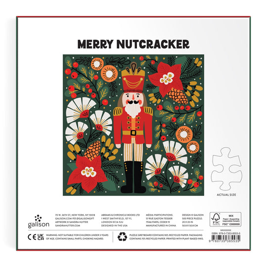 A vibrant nutcracker in a red uniform and crown, with festive flowers, decorates the Sandra Hutter Merry Nutcracker 500 Piece Foil Puzzle box. Merry Nutcracker and product details appear at the bottom alongside a single puzzle piece.