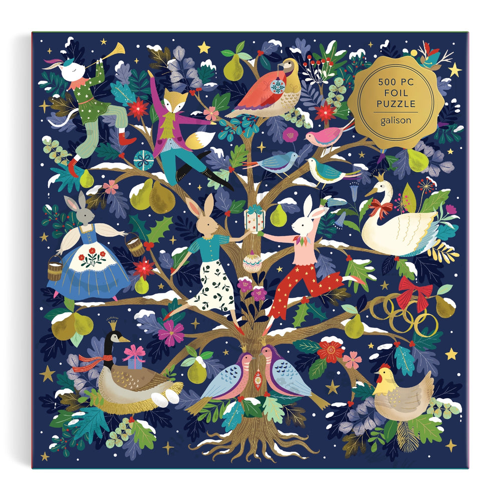 The 12 Days of Joy 500 Piece Foil Puzzle by Flora Waycott features animals like rabbits, birds, ducks, and a swan in festive outfits around a fruit and flower tree, adorned with stars. Box labeled: "500 Piece Foil Puzzle.