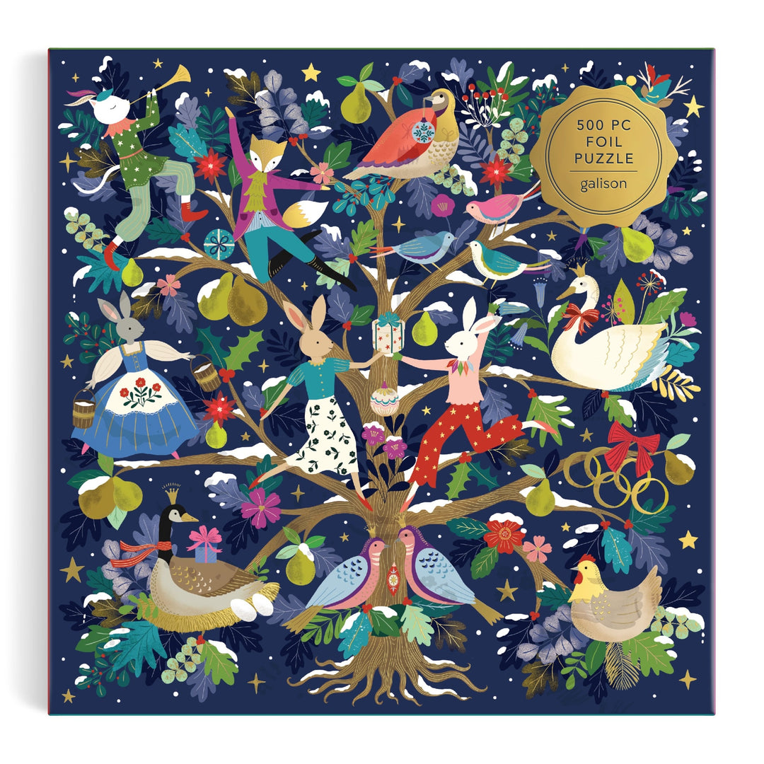 The 12 Days of Joy 500 Piece Foil Puzzle by Flora Waycott features animals like rabbits, birds, ducks, and a swan in festive outfits around a fruit and flower tree, adorned with stars. Box labeled: "500 Piece Foil Puzzle.