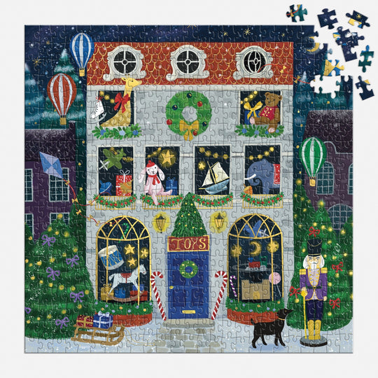 A partially completed Twilight Toy Shop 500 Piece Foil Puzzle by Bex Parkin shows a festive toy store with toys, hot air balloons, a nutcracker, black dog, presents, and Christmas trees. Several pieces are missing in the top right.