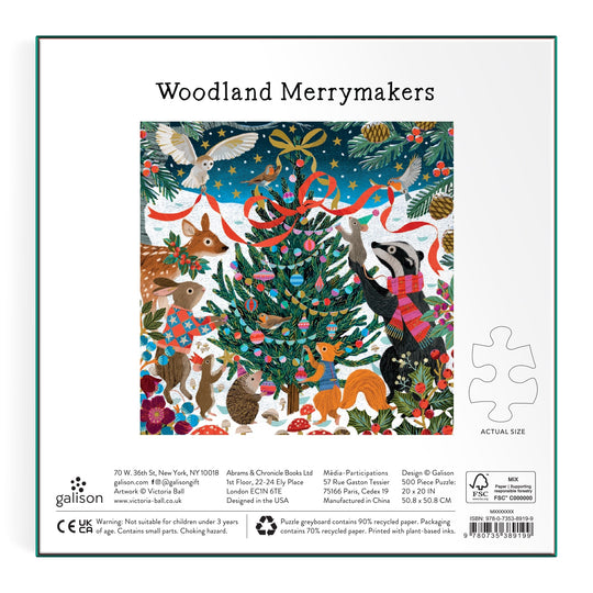 The Victoria Ball Woodland Merrymakers 500 Piece Foil Puzzle features woodland animals like a badger, rabbit, fox, and deer gathered at a festive Christmas tree in a snowy forest, with stars and birds above. Product info borders the vibrant illustration.