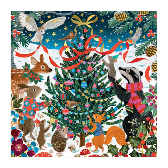 The Victoria Ball Woodland Merrymakers 500 Piece Foil Puzzle features a festive snowy forest with a badger, fox, deer, rabbit, mouse, hedgehog, and owl decorating a Christmas tree amid ornaments, red ribbons, pine branches, and flowers.