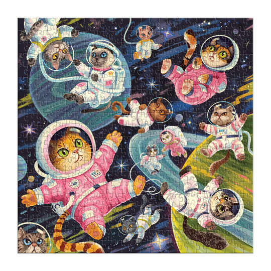 The Lucia Baertl "A Space Meowdyssey" 500-piece puzzle features cats in spacesuits with unique poses and expressions, floating among stars and planets against a dark space backdrop.