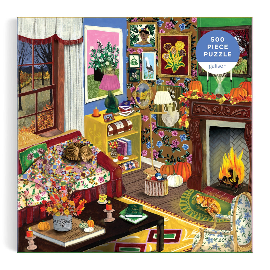 The "Fall is in the Air 500 Piece Puzzle" by Abbey Jacobs features a colorful autumn living room scene with a cat on a floral sofa, pumpkins, books, art, and a fireplace, all visible through a window with fall trees.