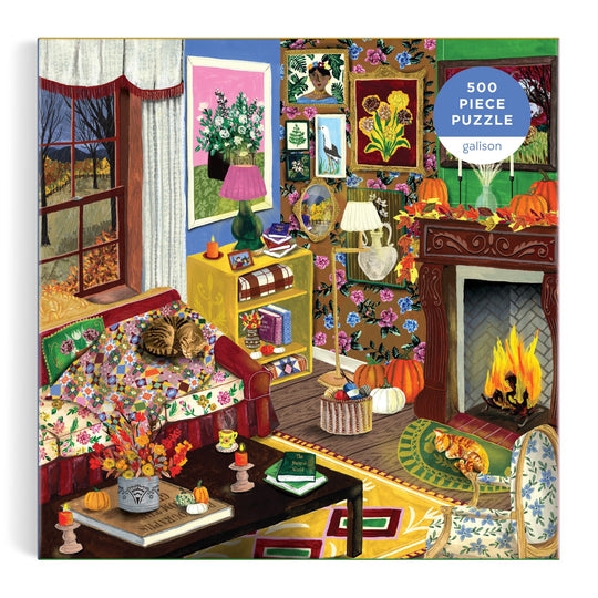 The "Fall is in the Air 500 Piece Puzzle" by Abbey Jacobs features a colorful autumn living room scene with a cat on a floral sofa, pumpkins, books, art, and a fireplace, all visible through a window with fall trees.