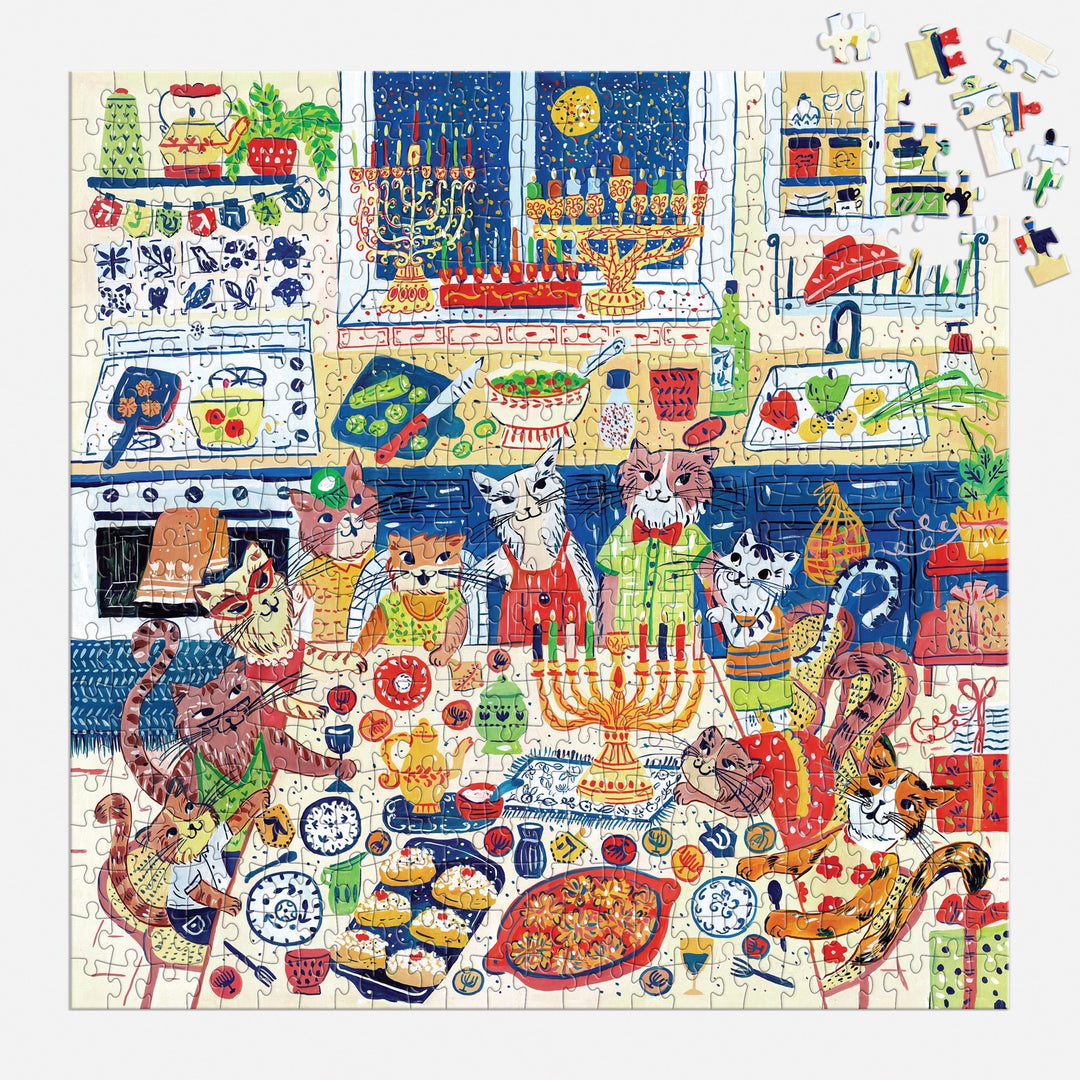 The Happy Hanukcats 500 Piece Puzzle by Anna Ivanir features cats in aprons celebrating Hanukkah in a kitchen with menorahs, lit candles, latkes, challah bread, and festive holiday decorations for a cheerful scene.