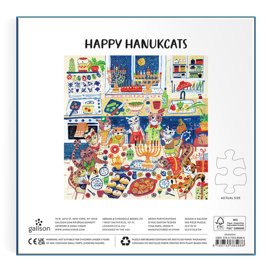 Celebrate Hanukkah with the Happy Hanukcats 500 Piece Puzzle by Anna Ivanir—adorable cats gather at a festive table with menorahs, dreidels, food, gifts, and decorations. The text above reads HAPPY HANUKATS—a perfect holiday puzzle!.