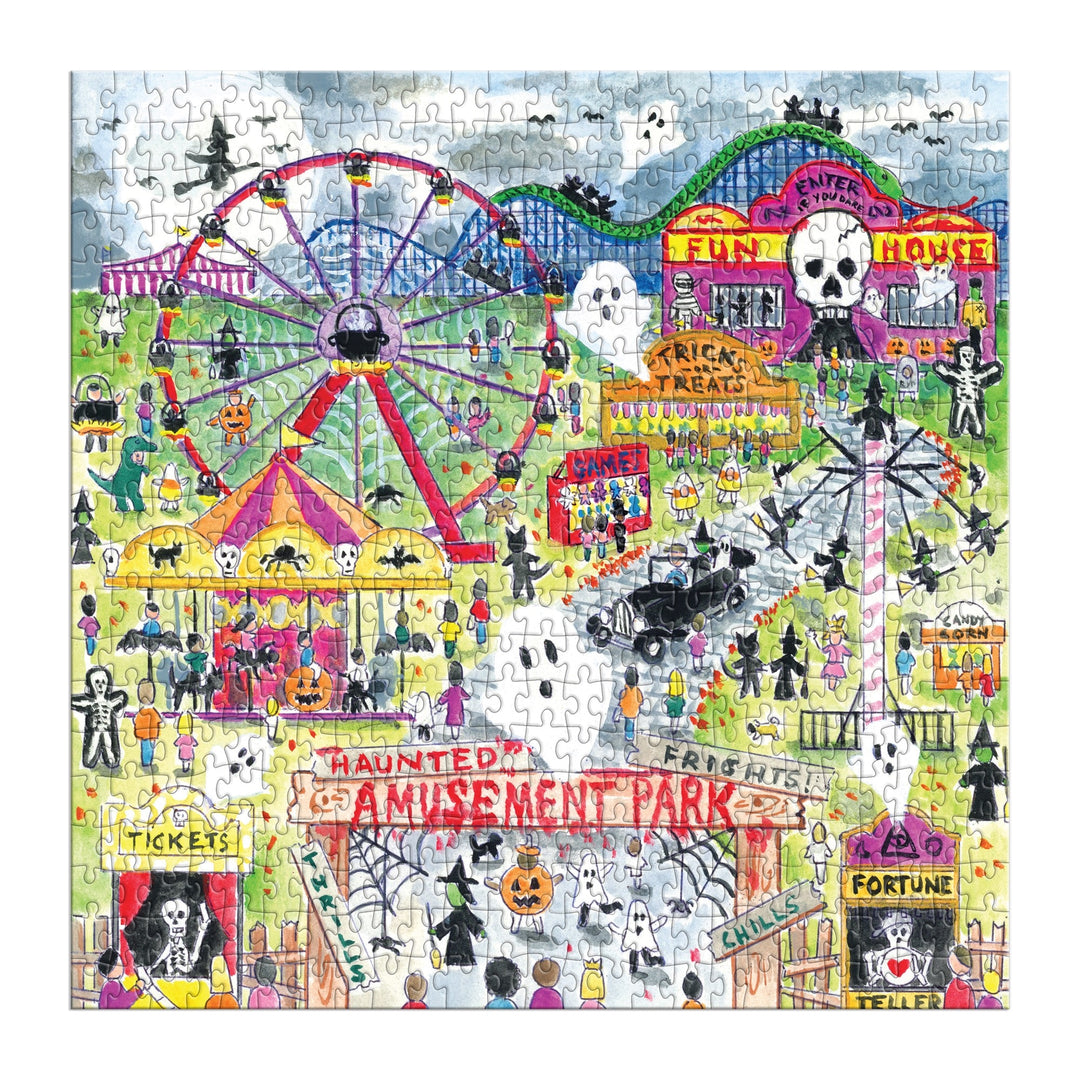 The Michael Storrings Haunted Amusement Park 500 Piece Puzzle features a vibrant Halloween scene with costumed visitors, pumpkins, a haunted house, ferris wheel, fortune teller, carnival stands, and festive skull and skeleton decorations.