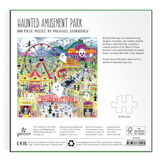 The back of the box features vibrant artwork of an amusement park with rides, ferris wheel, haunted house, and visitors. Text includes the title "Michael Storrings Haunted Amusement Park 500 Piece Puzzle" and artist info.