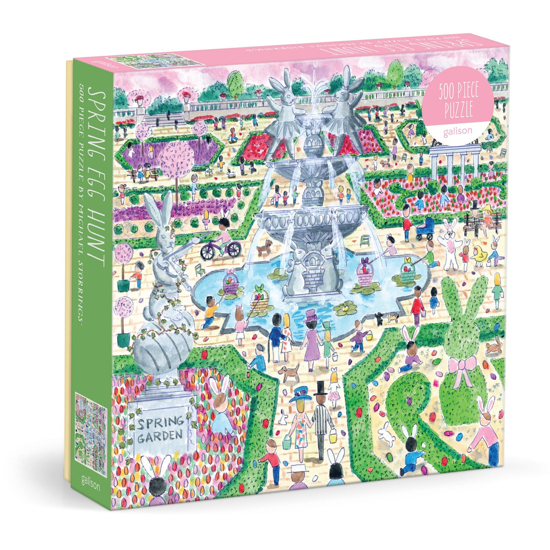 The Michael Storrings Spring Egg Hunt 500 Piece Puzzle by Michael Storrings features a vibrant spring garden scene with people, large rabbits, eggs, flowers, trees, a decorative fountain, and a glass jar labeled "Spring Garden.