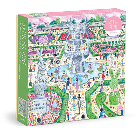 The Michael Storrings Spring Egg Hunt 500 Piece Puzzle by Michael Storrings features a vibrant spring garden scene with people, large rabbits, eggs, flowers, trees, a decorative fountain, and a glass jar labeled "Spring Garden.