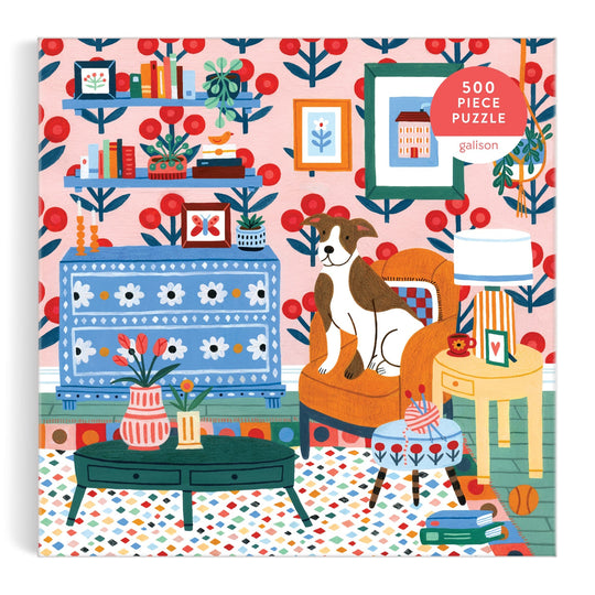 Pattern & Petal 500 Piece Puzzle by Molly Egan features a vibrant living room scene with patterned wallpaper, bookshelves, a blue table, flower vases, an orange armchair with a dog, and playful decor.