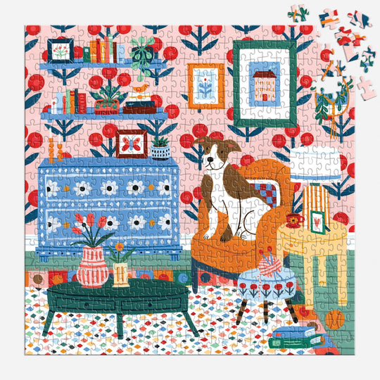 The Pattern & Petal 500 Piece Puzzle by Molly Egan features a cozy room with a dog on an orange chair, bookshelves, plants, colorful furniture on a patterned rug, and depicts the scene with a few pieces still missing.