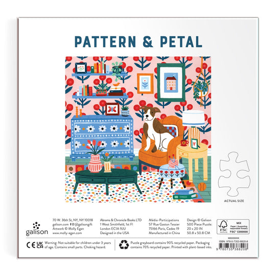 A vibrant illustration by Molly Egan decorates the back of the Pattern & Petal 500 Piece Puzzle box, featuring a cozy living room with patterned wallpaper, blue and orange furniture, a cat on the sofa, plants, lamps, and framed art.