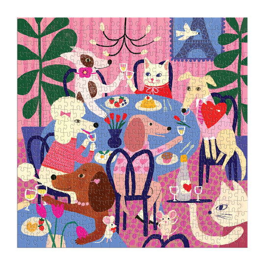 The Anne Bentley Paws for Love 500 Piece Puzzle features six dogs gathered around a dining table in a vibrant, plant-filled room with pink walls—an ideal, cheerful gift for dog lovers.