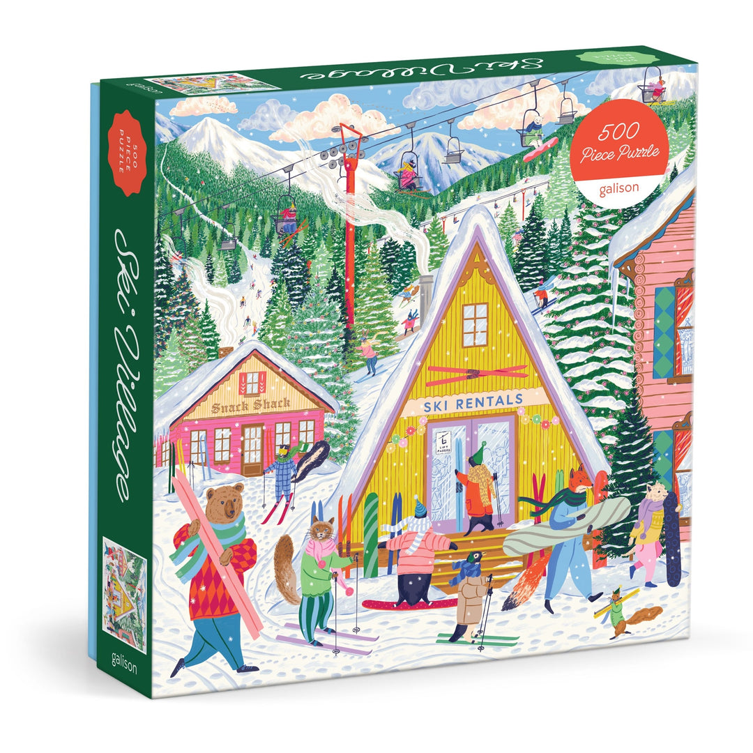 The Emily Taylor Ski Village 500 Piece Puzzle features a vibrant ski village scene with people in winter attire, snow-covered trees, ski lifts, buildings labeled "Ski Rentals" and "Snack Shack," and a scarf-wearing bear carrying skis.