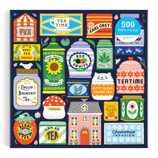 The Spot of Tea 500 Piece Puzzle by Holly Maguire features a vibrant cover illustration of assorted tea tins and boxes circling a small house on a dark blue background.