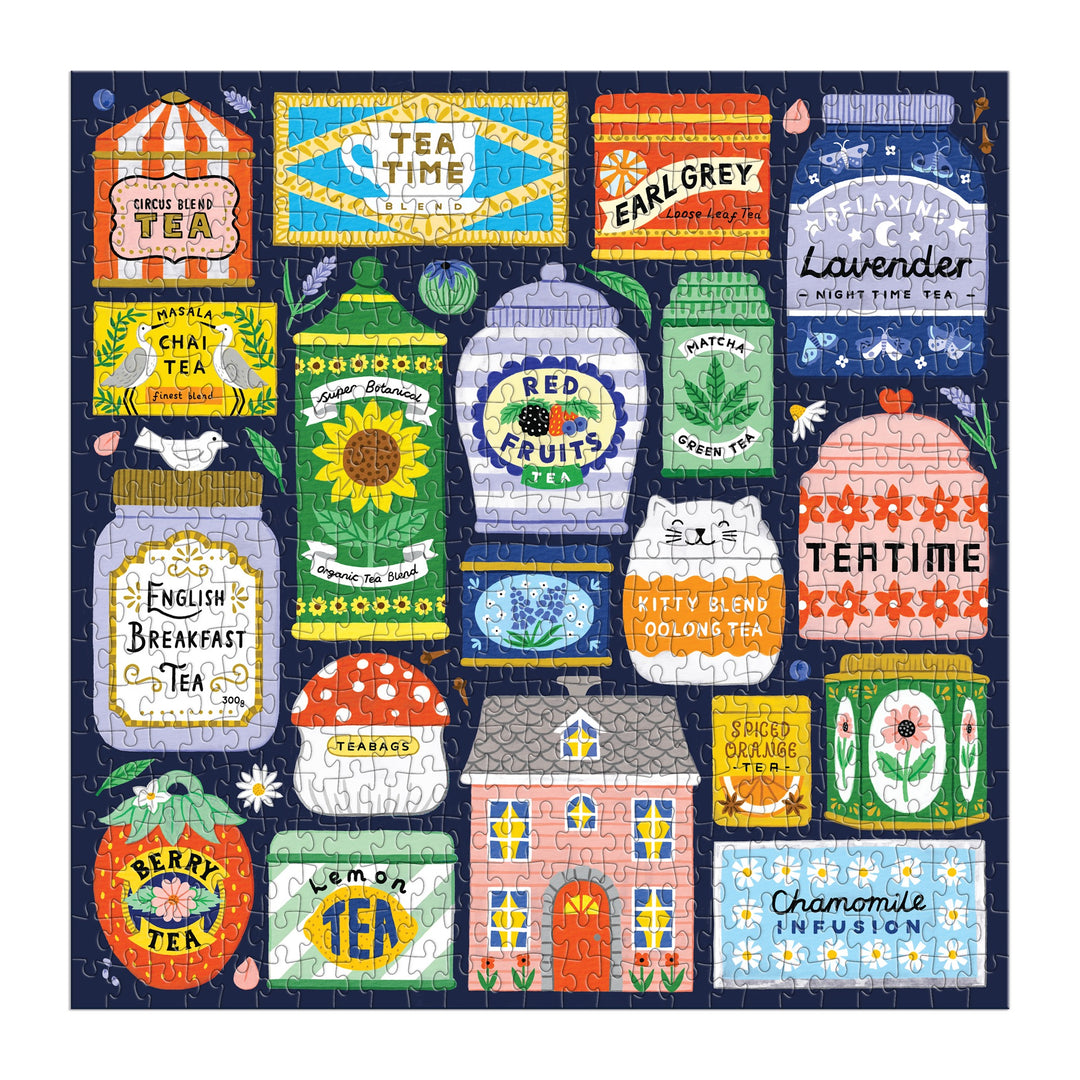 The Spot of Tea 500 Piece Puzzle by Holly Maguire features vibrant tea-themed artwork with illustrated tins and boxes labeled earl grey, chai, green tea, berry, chamomile, plus a decorated house at the center.