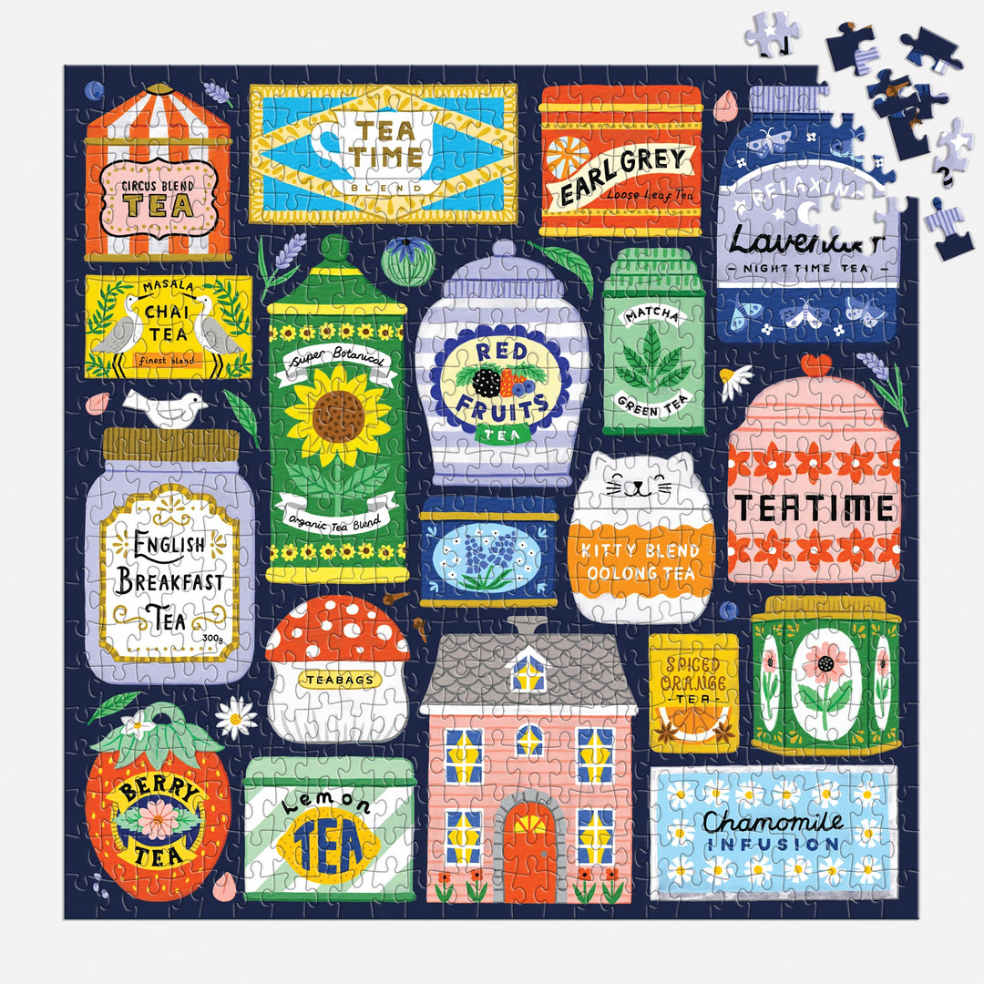 A nearly finished Spot of Tea 500 Piece Puzzle by Holly Maguire displays vibrant tea tins—Earl Grey, Red Fruits, Matcha, Chai, Berry, Chamomile—with a few pieces left in the top right corner.