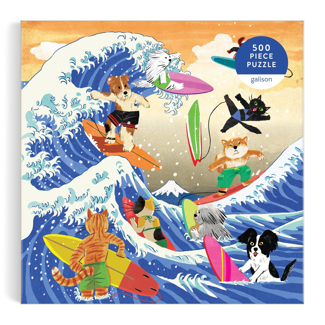 Yeji Yun’s The Great Surf 500 Piece Puzzle features cats and dogs riding vibrant surfboards on big ocean waves, a mountain in the background, and a “500-piece puzzle” label in the corner.