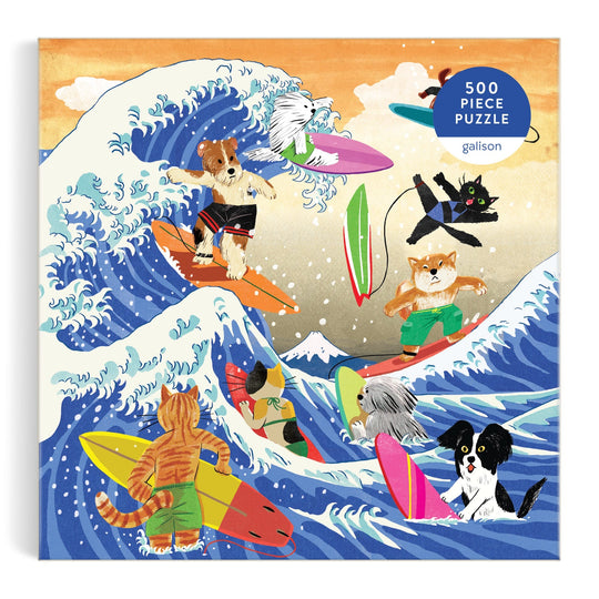 Yeji Yun’s The Great Surf 500 Piece Puzzle features cats and dogs riding vibrant surfboards on big ocean waves, a mountain in the background, and a “500-piece puzzle” label in the corner.