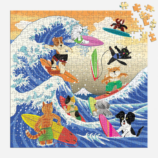 The Great Surf 500 Piece Puzzle by Yeji Yun features cartoon cats and dogs surfing on waves with surfboards, set against blue skies and mountains. Some pieces are scattered in the top right corner.