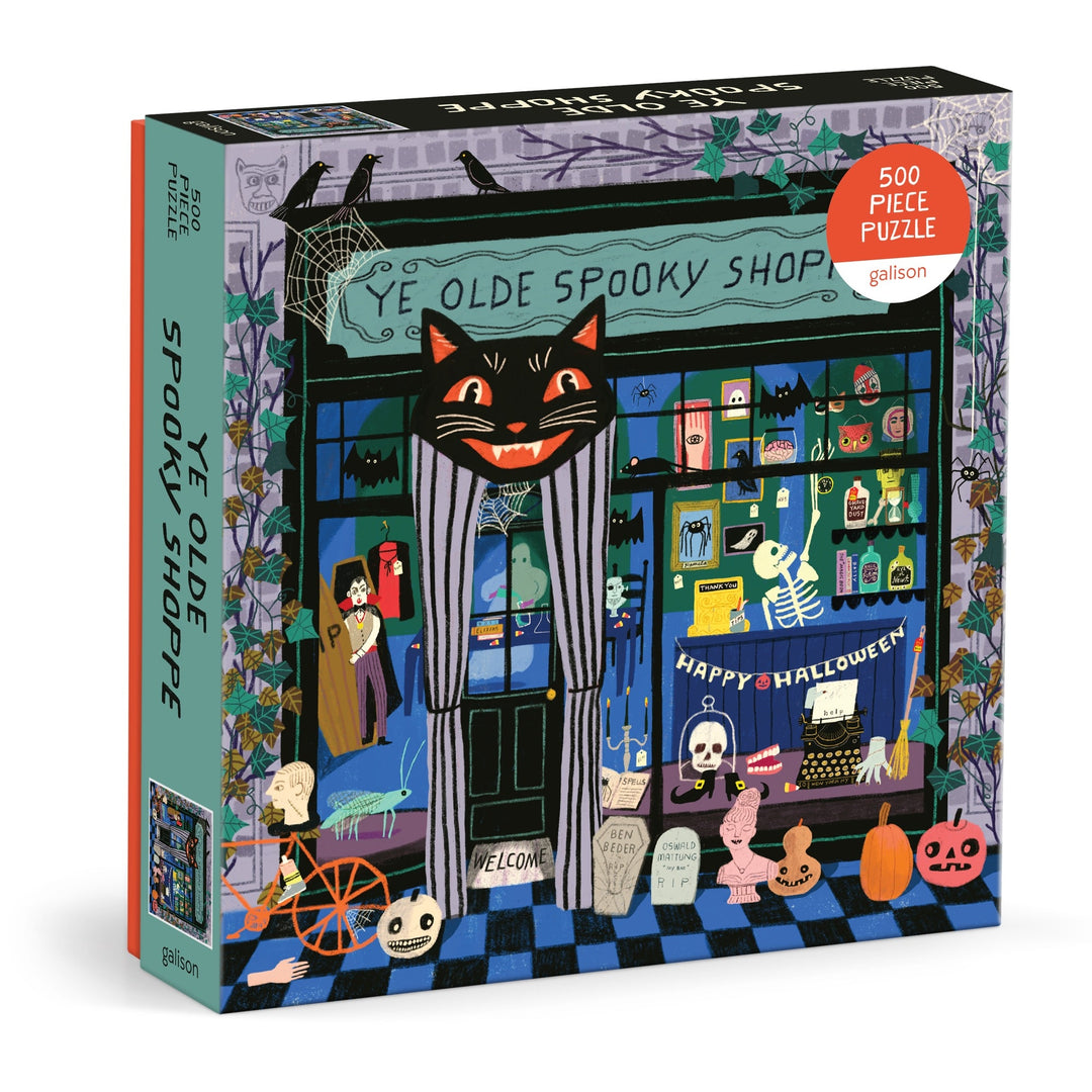 The Anne Bentley Ye Olde Spooky Shoppe 500 Piece Puzzle features a vibrant Halloween shop scene with a black cat sign, ghosts, pumpkins, skeletons, and festive decorations.