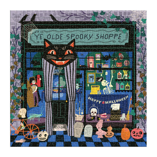 The Anne Bentley Ye Olde Spooky Shoppe 500 Piece Puzzle features a Halloween store scene with a grinning cat sign, skeletons, potions, cobwebs, pumpkins, and spooky items in the window and outside.