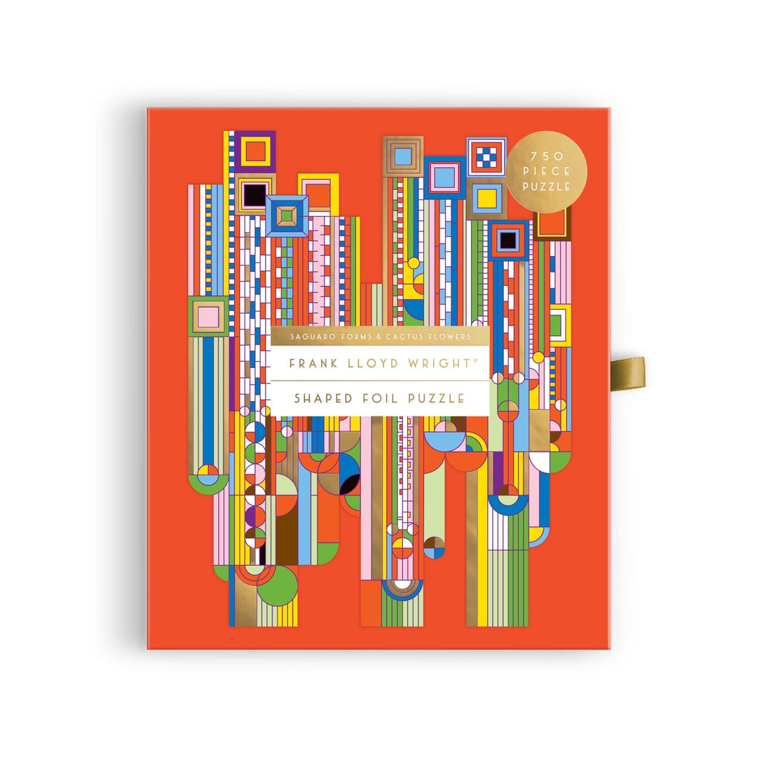 A bright orange puzzle box features a colorful geometric design inspired by Frank Lloyd Wright, with bold shapes and foil accents. The label reads “Frank Lloyd Wright Foundation Saguaro Cactus & Forms 750 Piece Shaped Foil Puzzle.”.