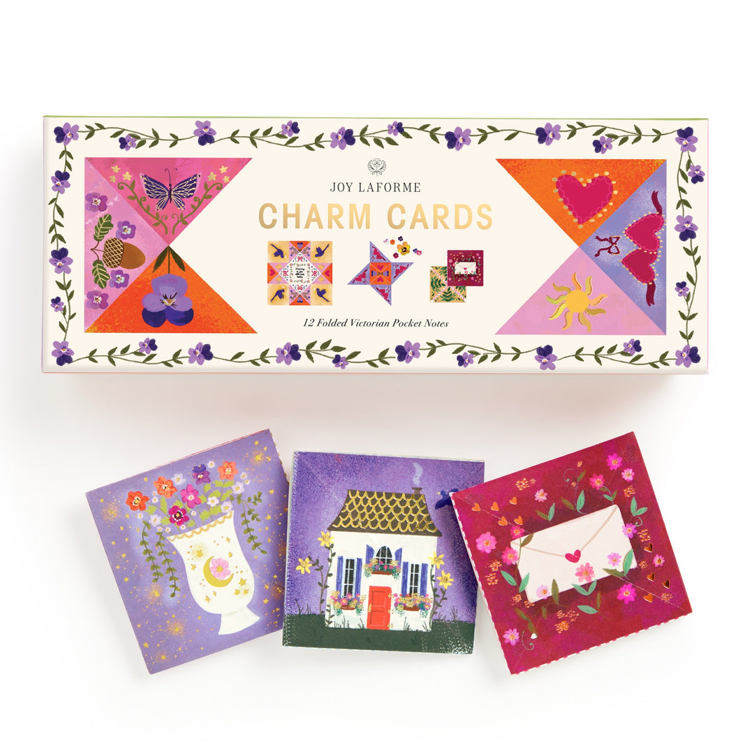 A box labeled Joy Laforme Charm Cards by Joy Laforme features floral decorations and colorful designs. Three small folded cards below showcase refined stationery, perfect for sophisticated correspondence.