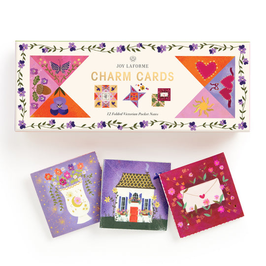 A box labeled Joy Laforme Charm Cards by Joy Laforme features floral decorations and colorful designs. Three small folded cards below showcase refined stationery, perfect for sophisticated correspondence.