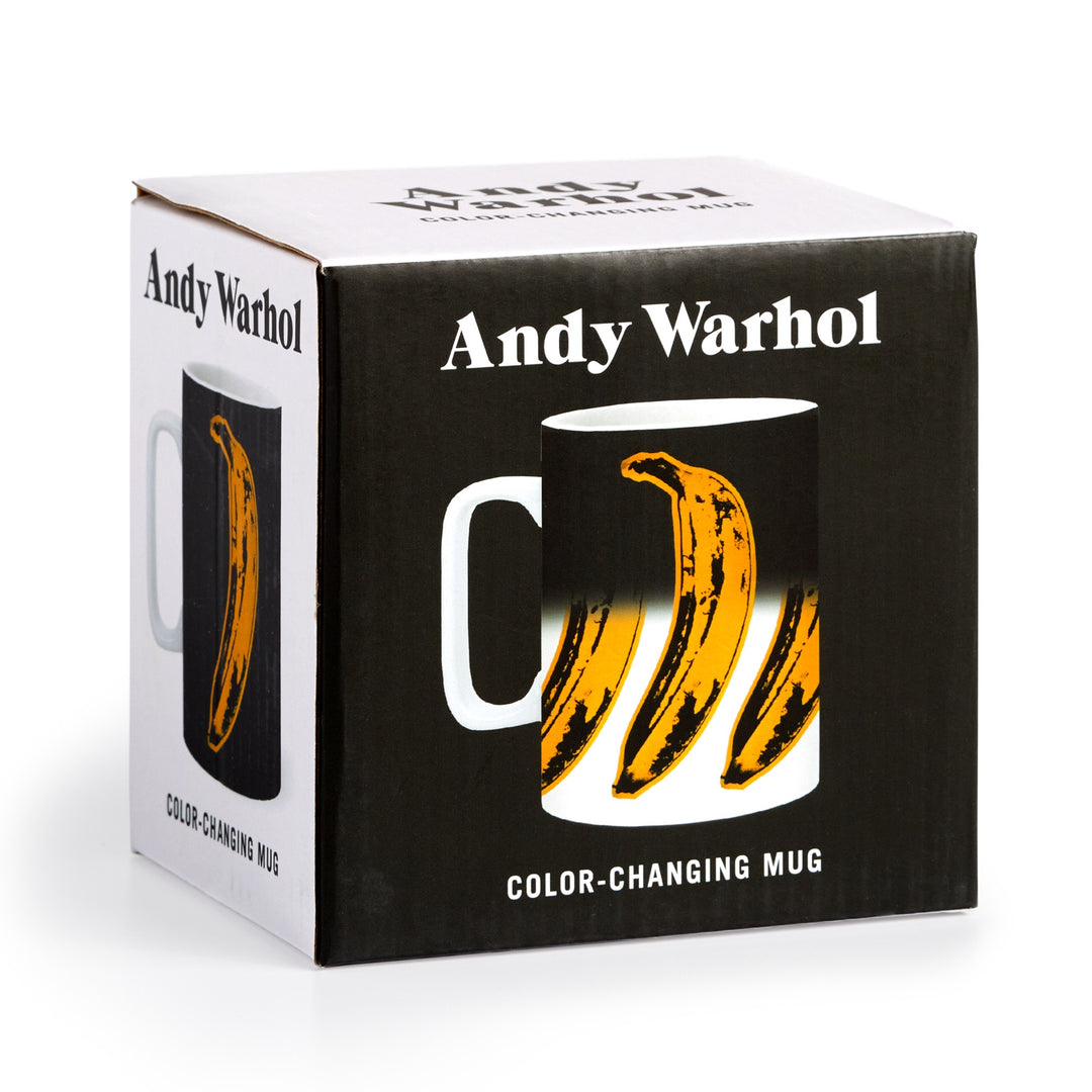 A box labeled “Andy Warhol” displays the Andy Warhol Banana Color Changing Ceramic Mug, featuring the iconic yellow banana design that appears on the black mug when hot liquid is added.