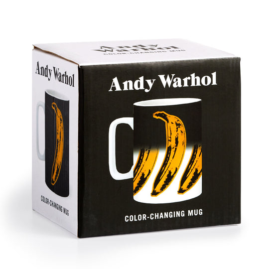 A box labeled “Andy Warhol” displays the Andy Warhol Banana Color Changing Ceramic Mug, featuring the iconic yellow banana design that appears on the black mug when hot liquid is added.