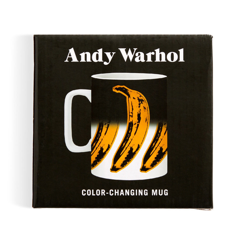 A product box for the Andy Warhol Banana Color Changing Ceramic Mug by Andy Warhol shows a mug with a yellow banana design in Warhol’s pop art style, labeled Andy Warhol at the top and Color-Changing Mug at the bottom.