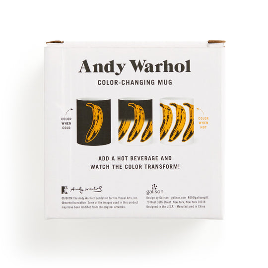 A white box showcases the Andy Warhol Banana Color Changing Ceramic Mug by Andy Warhol. The mug’s yellow banana graphic changes color with heat, as described in the text about its transformation when a hot drink is poured inside.