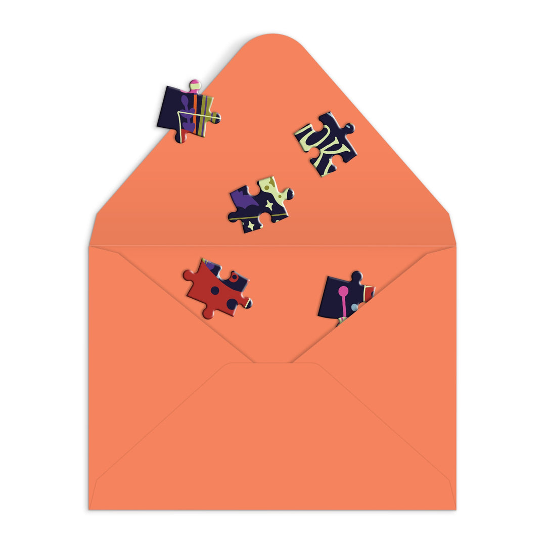 An open envelope with six colorful puzzle pieces surrounds the Get into the Spooky Spirit Greeting Card Puzzle by Camille Chew—an interactive greeting card on a white background.